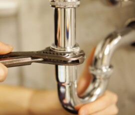 Plumbing repair service. Professional installer with spanner checking pipe.