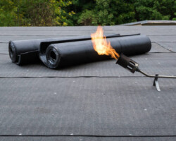 Heating and melting bitumen roofing felt Flat roof installation.