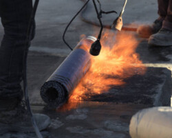Laying of roofing felt from the roll with a flame from the burner close-up.