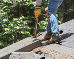 Man removing old shingles on roof. Installing new roof.